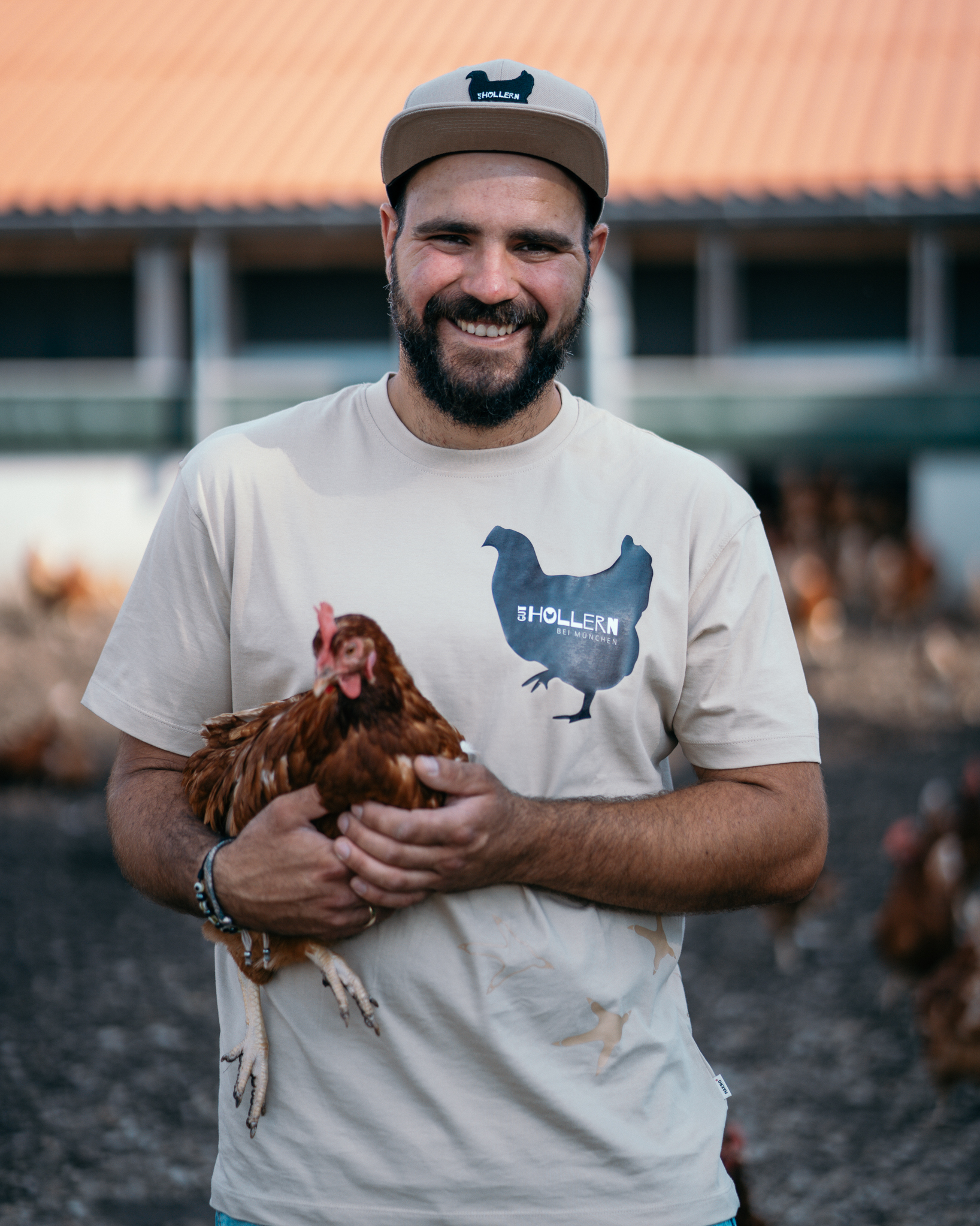 Bauer Niko auf Gut Hollern mit einem glücklichen Huhn auf den Arm